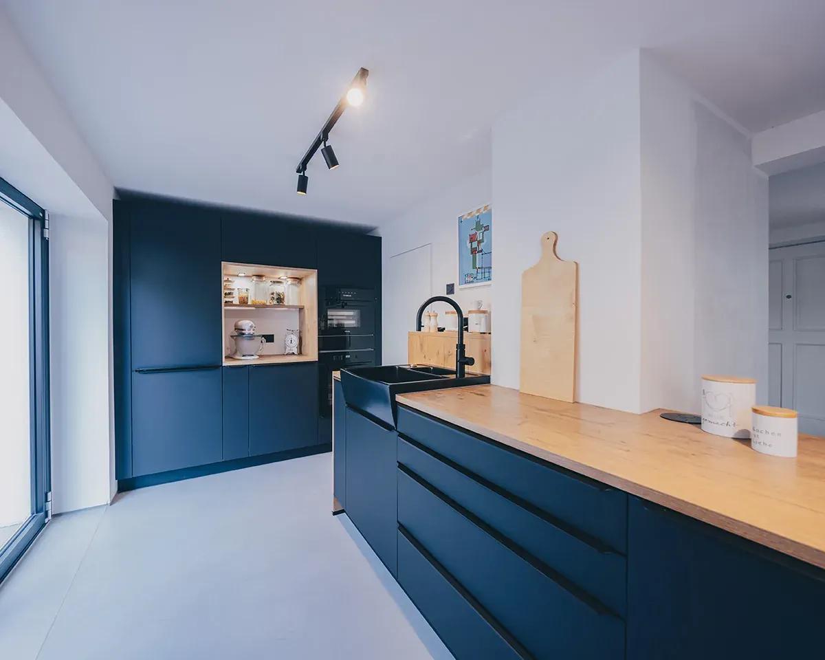 Designküche mit schwarzer Kücheninsel und Holzarbeitsplatte
